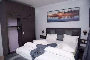 基加利Grazia Apartments的一间卧室设有两张床,墙上挂着一幅画
