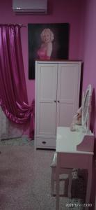 帕拉比塔VILLA DAILA的粉红色的房间,配有白色的橱柜和一张桌子