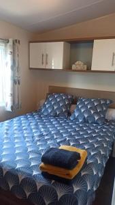 维亚斯Mobil-home FO 88 à VIAS的一间卧室配有蓝色的床,上面有黄色的搁脚凳