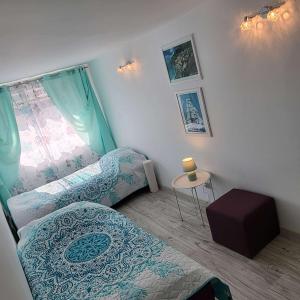 什切青Carpe Diem Lakeside Apartment的客房设有两张床、一张桌子和一扇窗户。