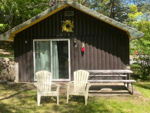 乔治湖Amber Lantern Two-Bedroom Cottage的小屋前设有两把椅子和一张野餐桌