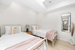 贝尔维尔The Belvedere:Front Street Flats的一间白色卧室,配有两张床和镜子