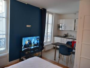 凡尔赛Le Studio Versaillais的一间设有蓝色墙壁、电视和桌子的房间