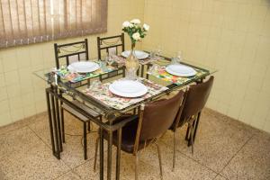 贝洛奥里藏特Casa espaçosa e confortável na região da Pampulha的一张带椅子和盘子的玻璃桌和花瓶