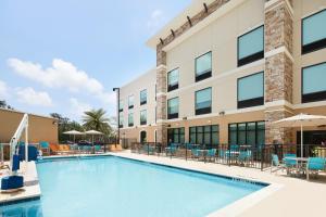 微风湾Holiday Inn Express & Suites Gulf Breeze - Pensacola Area, an IHG Hotel的一座带椅子和遮阳伞的大楼前的游泳池