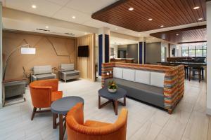 微风湾Holiday Inn Express & Suites Gulf Breeze - Pensacola Area, an IHG Hotel的大堂设有橙色椅子和钢琴