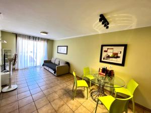 拉特吉塔Apartment in La Tejita (El Medano)的客厅配有玻璃桌和黄色椅子