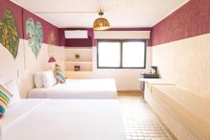 坎昆Selina Cancun Laguna Hotel Zone的一间卧室设有两张床、一个浴缸和一个窗口。