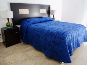 布塞里亚斯Casa Los Amores的一张蓝色的床,上面有黑色床头板和蓝色的毯子