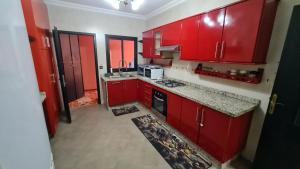 马拉喀什Apartamento Centro Guéliz的红色的厨房配有红色橱柜和微波炉