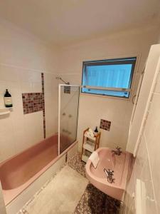 卡伦德拉Beach House @ Moffat的一间带粉色浴缸和水槽的浴室