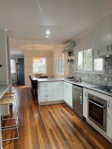卡伦德拉Beach House @ Moffat的厨房铺有木地板,配有白色橱柜。