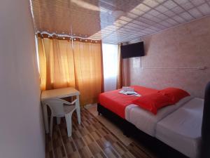 波哥大HOTEL BOGOTA AIRPORT DORADO的一间卧室配有红色的床、一张桌子和一张书桌