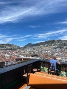 基多Hostal La Guayunga RoofTop的坐在俯瞰城市的阳台上的人