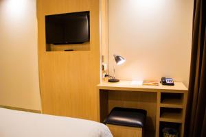 如奈Cassowary Hotel的酒店客房配有一张床和一张书桌及一台电视
