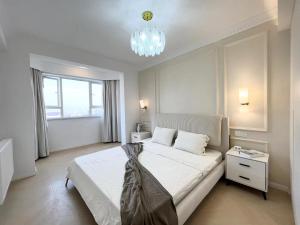 上海黄浦滨江奶油风四房设计师江景公寓的卧室配有一张带吊灯的大型白色床。