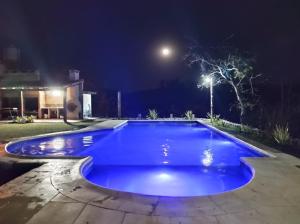 罗萨里奥德拉弗龙特拉Hostería La María的夜间蓝色游泳池,有街灯