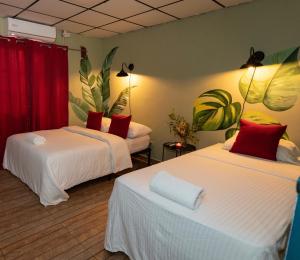 圣地亚哥Hostel Travelers Santiago的配有红色窗帘和植物的客房内的两张床
