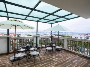 下龙湾Ha Long Essence Classic Hotel的阳台的天井配有桌椅和遮阳伞。