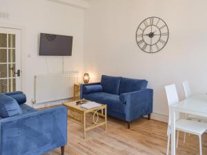 艾尔The Secret Garden的客厅配有蓝色的沙发和墙上的时钟