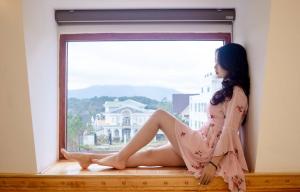大叻Hoàng Yến Villa Dalat的坐在窗台上穿着裙子的女人