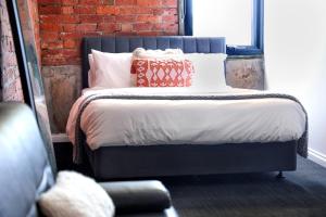 墨尔本Bayside House的一间卧室配有带枕头的床和砖墙