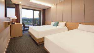 春川Chuncheon Eston Hotel的酒店客房设有两张床和电视。