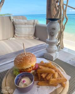 查汶Elephant Beach Club & Resort Samui的餐桌上放着汉堡包和炸薯条,海滩上放着