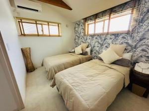 北谷町ResortHouse-KAPUKA的一间卧室设有两张床和窗户。
