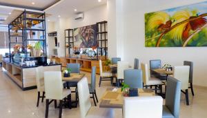 索龙Vega Prime Hotel & Convention的餐厅设有桌椅,墙上挂有绘画作品