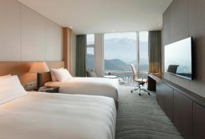 济州市LOTTE City Hotel Jeju的酒店客房设有两张床和一台平面电视。