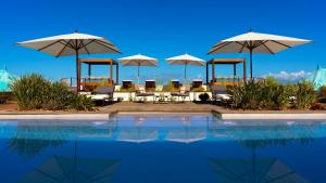 圣勒蓝色马古拉特海景酒店 - 罗莱夏朵精品酒店集团的一个带桌子、遮阳伞和椅子的游泳池