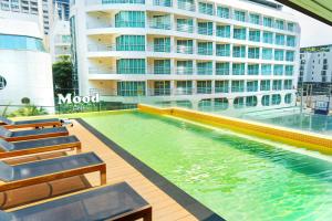 芭堤雅市中心Mood Hotel Pattaya的大楼前的游泳池