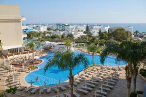 普罗塔拉斯Sunrise Oasis Hotel & Waterpark的享有带椅子和棕榈树的游泳池的景色