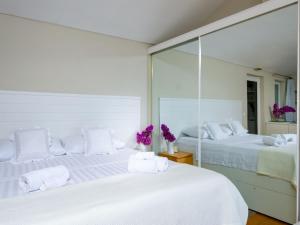 洛帕德Villa Lola的白色卧室配有两张带镜子的床