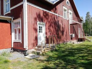 KorsnäsVindsvåning i Harrström的一间红色的房子,上面有白色的门和楼梯