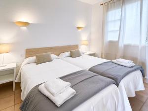 桑坦德利亚湾Grupoandria Aparthotel Club Andria的白色卧室内的两张床,配有毛巾
