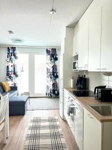 奥卢Kotimaailma Apartments Sairaalanrinne的厨房配有白色橱柜和蓝色沙发