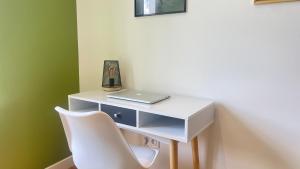 尼奥尔Le Vert’ueux - Appartement tout équipé à Niort的一张带笔记本电脑和白色椅子的白色书桌