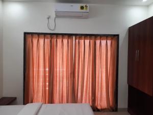 马尔万Raapan Beach Resort的一间卧室配有橙色窗帘和电视