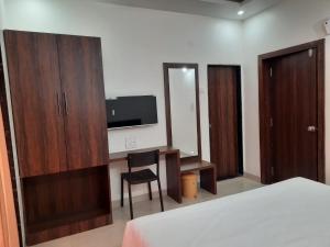 马尔万Raapan Beach Resort的一间卧室配有书桌、电视和椅子