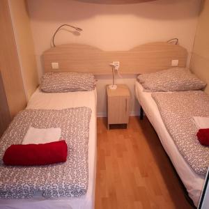 比奥格勒·纳·莫鲁Camping Park Soline - Rose PB -Mobile Home的客房设有两张床和一张带红色枕头的桌子。