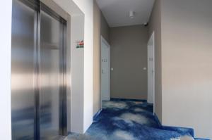 尤斯托尼莫斯基Apartament z widokiem na morze - Nadmorski Luksus Apartamenty的一条空的走廊,有门和蓝色的地毯