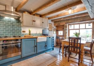 罗宾胡兹贝Green Cottage的厨房配有蓝色橱柜和桌椅