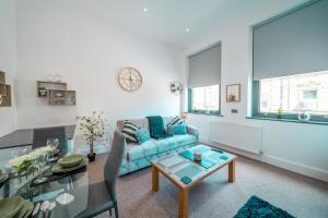 巴恩斯利Cozy 1-Bedroom Apartment in the Heart of Barnsley Town Centre的客厅配有蓝色的沙发和玻璃桌