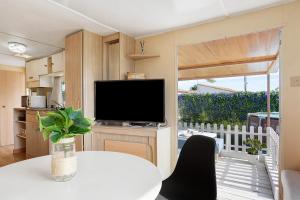 奇克拉纳－德拉弗龙特拉Villa Triana的客厅配有电视和带桌子的白色桌子。