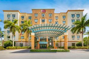 肯代尔Best Western Plus Miami Executive Airport Hotel and Suites的拥有棕榈树的大型建筑的酒店