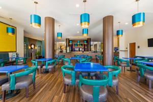 肯代尔Best Western Plus Miami Executive Airport Hotel and Suites的一间设有蓝色桌椅的餐厅