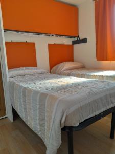 阿菲Agricampeggio Le Corniole的橙色墙壁客房的两张床