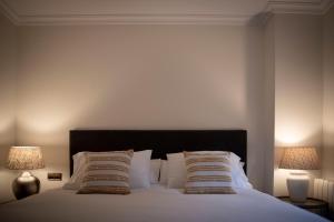 圣洛伦索-德埃斯科里亚尔Apartamento Exterior 2 dormitorios en CENTRO HISTÓRICO的一间卧室配有一张带枕头的床和两盏灯。